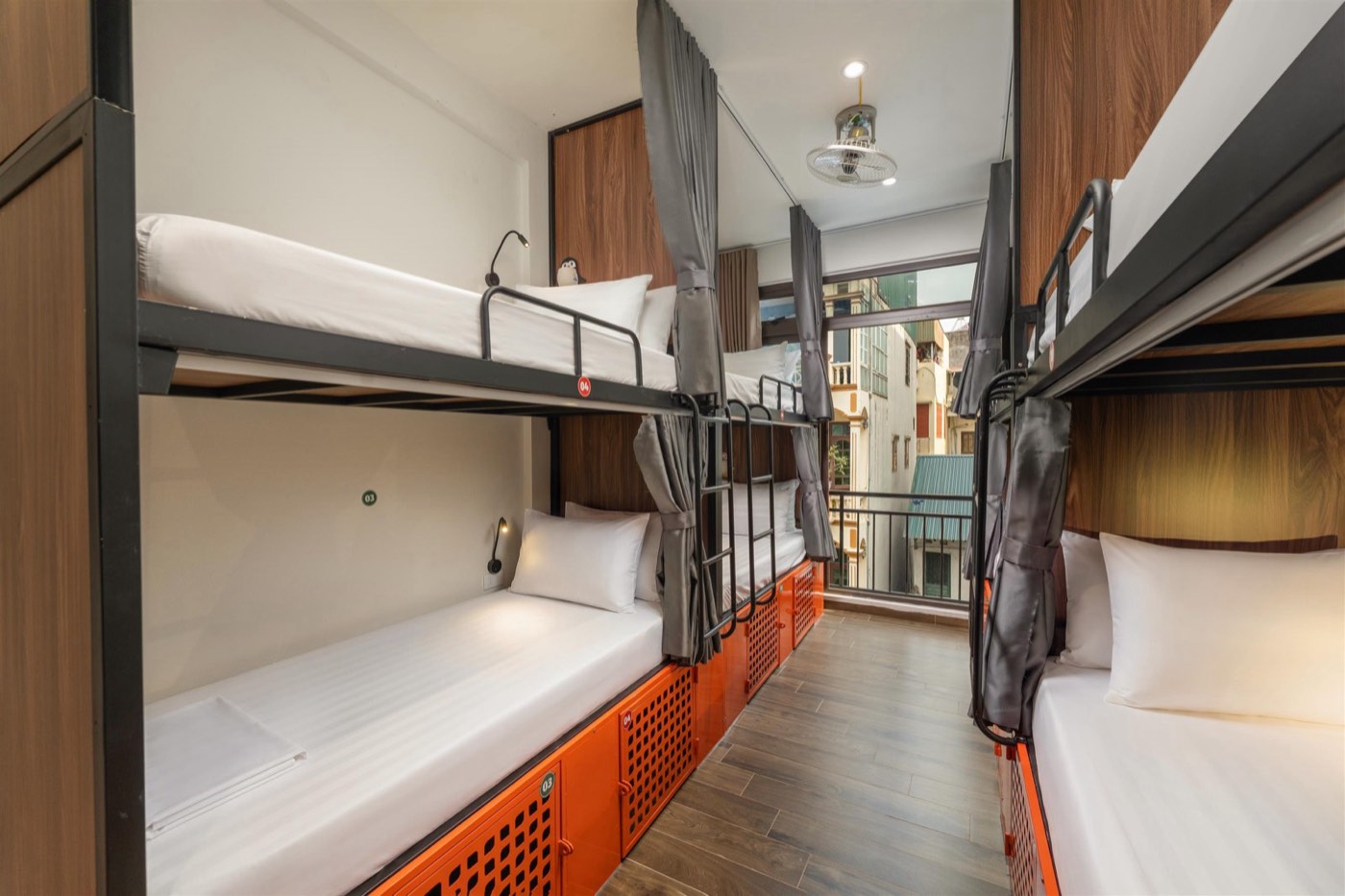 Steel bunks with privacy curtains and orange lockers, photo from floor 3, same layout